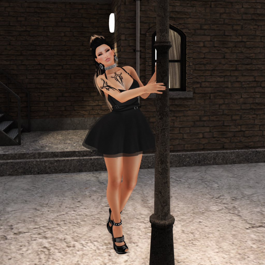 A female Second Life avatar with tattoos dances in a Black dress and smiles at the camera.